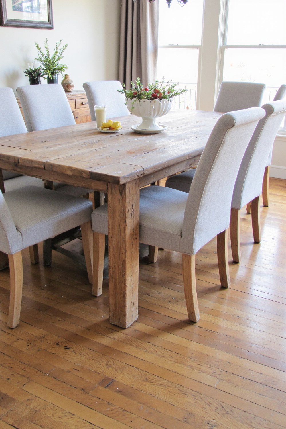 Neutral upholstered dining chairs - Neutral Linen Dining Chairs: Rustic Wood Table Setting - Eight light gray linen dining chairs surround a...