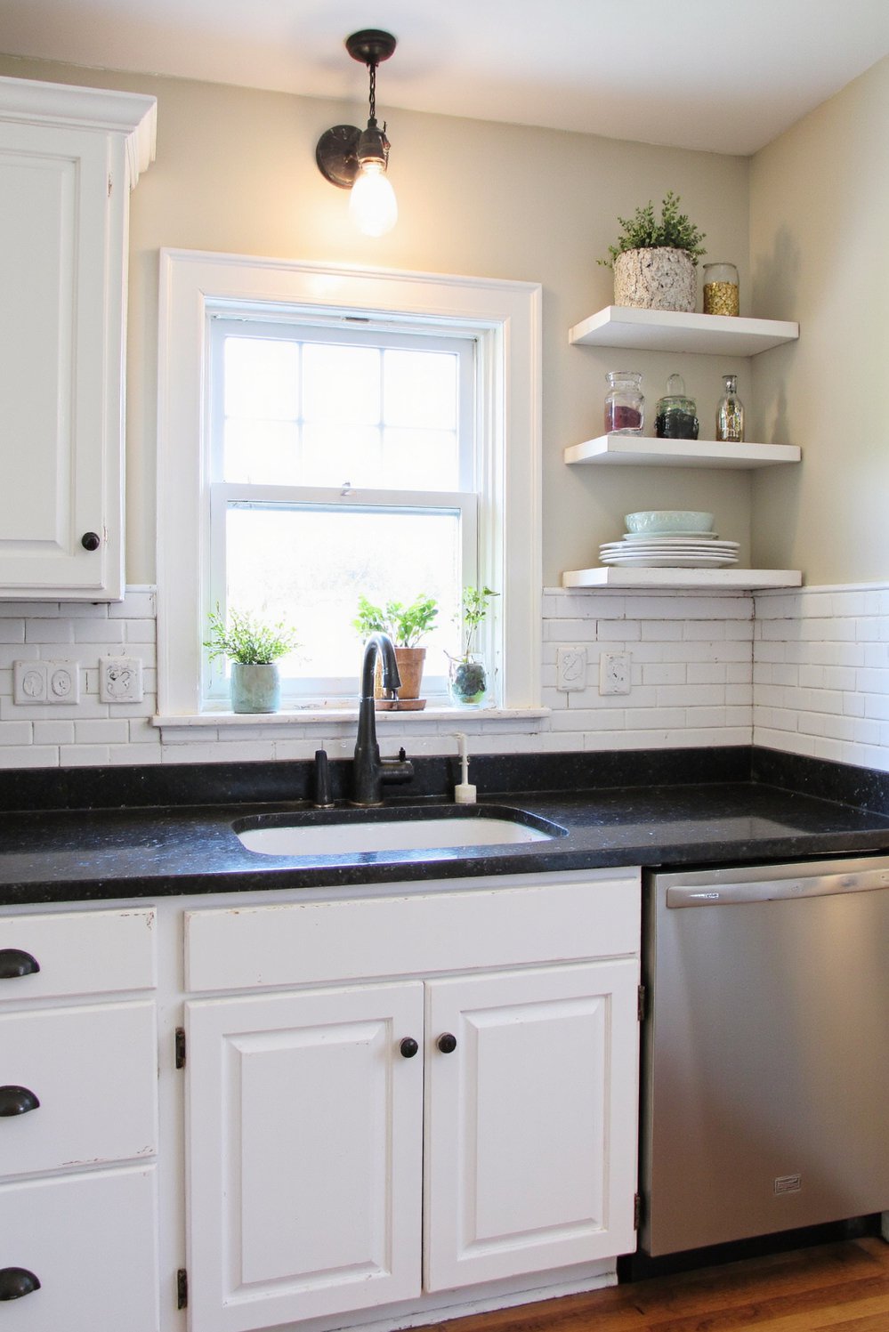 Black and White Modern Kitchen - Farmhouse White Kitchen: Black Countertops, Modern Twist - Farmhouse kitchen with black countertops. White cabinets and...