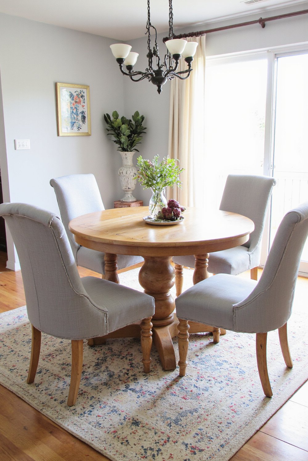 Neutral upholstered dining chairs - Light Gray Linen Dining Chairs: Round Wood Table Setting - Four light gray linen dining chairs gather around...