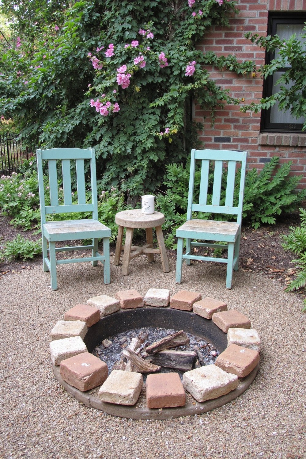 Fire pit patio ideas - Whimsical Cottage Fire Pit with Climbing Plants - Charming cottage-style fire pit. A small, round painted...