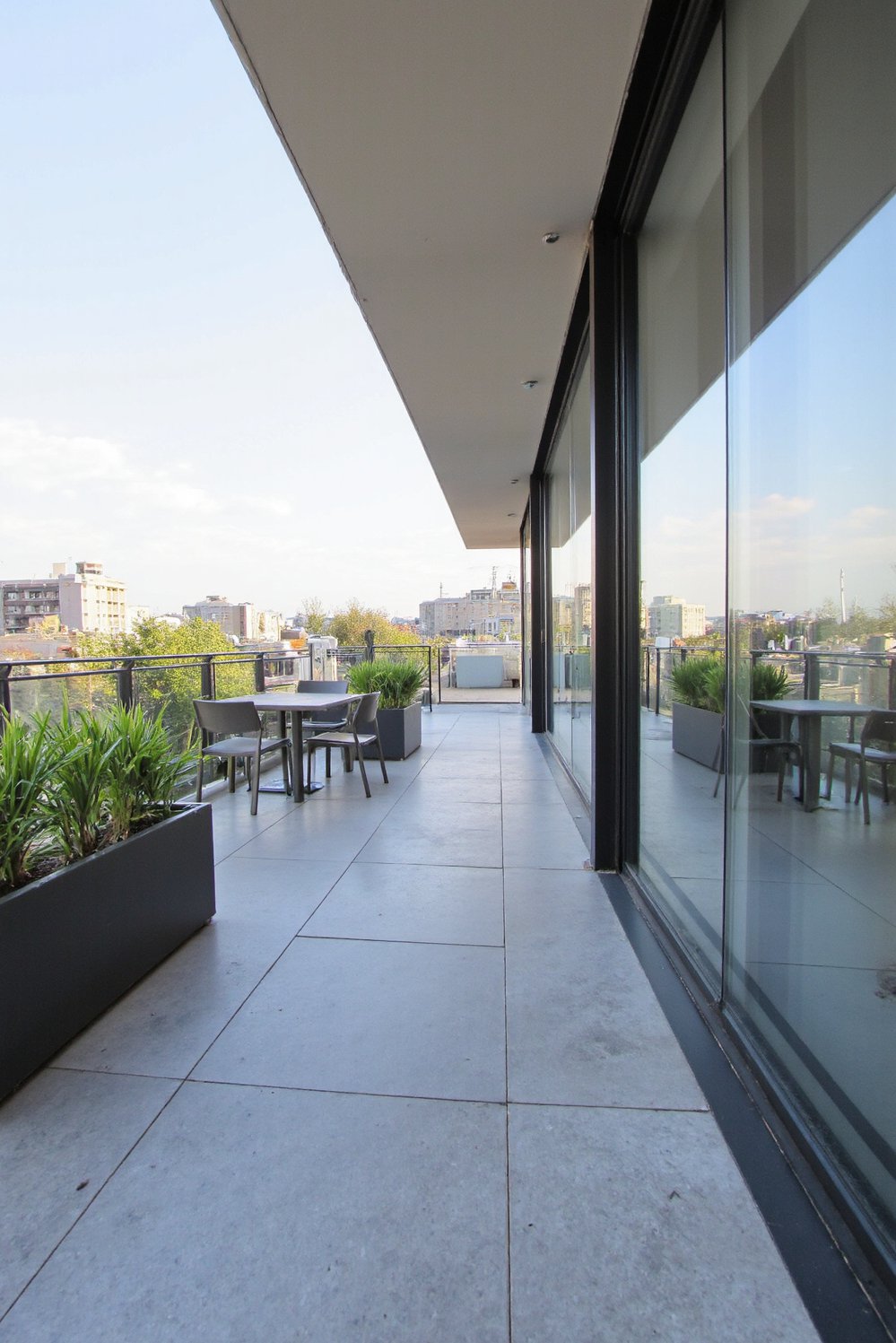 Balcony flooring ideas - Modern Balcony Flooring: Sleek Grey Stone & Planters - Sleek, grey polished stone flooring creates a modern...
