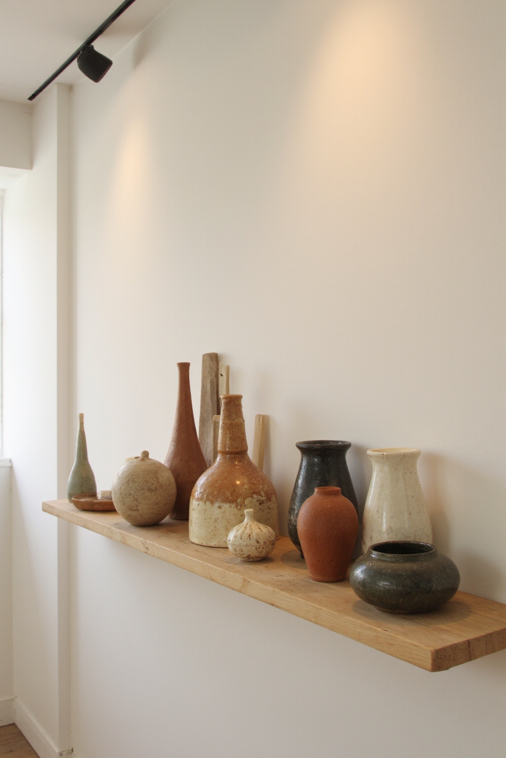 end of hallway decor - Curated Ceramic Hallway Gallery - A long, light wood shelf floats serenely at...